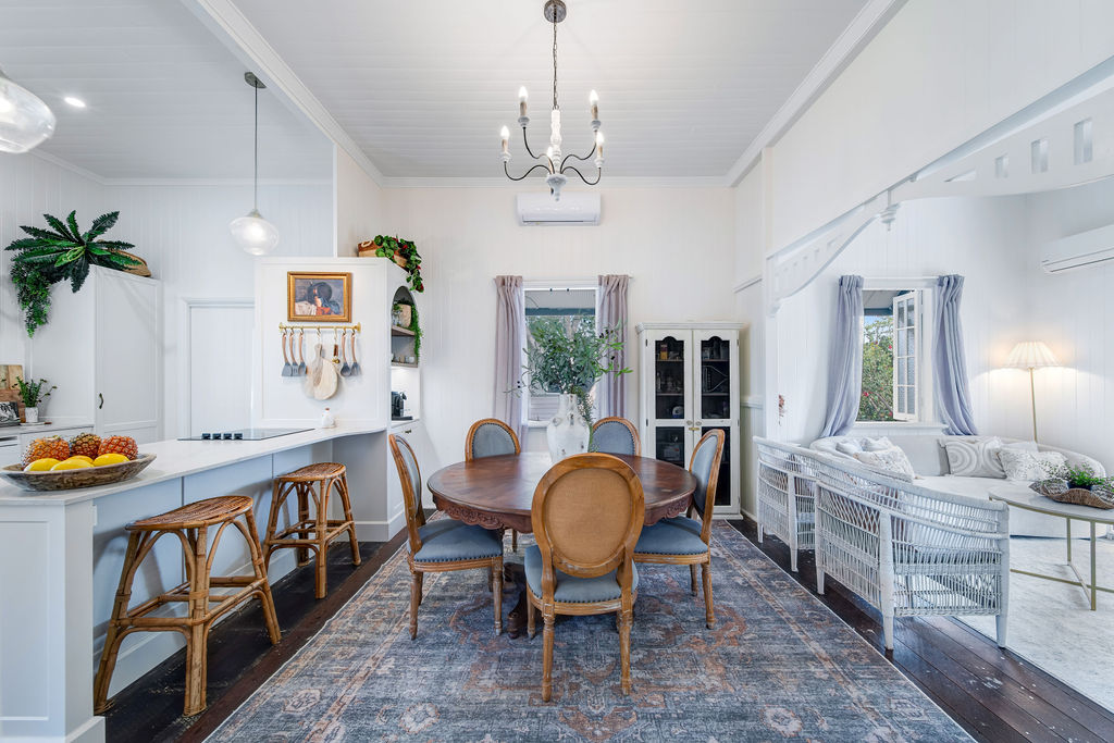 Dining room with restored timber floors, chandelier, timber dining chairs and open flow to the living room.