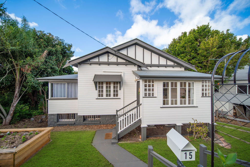 The exterior after renovation, repainted white with grey trim, a refreshed entry path and tidy garden beds.