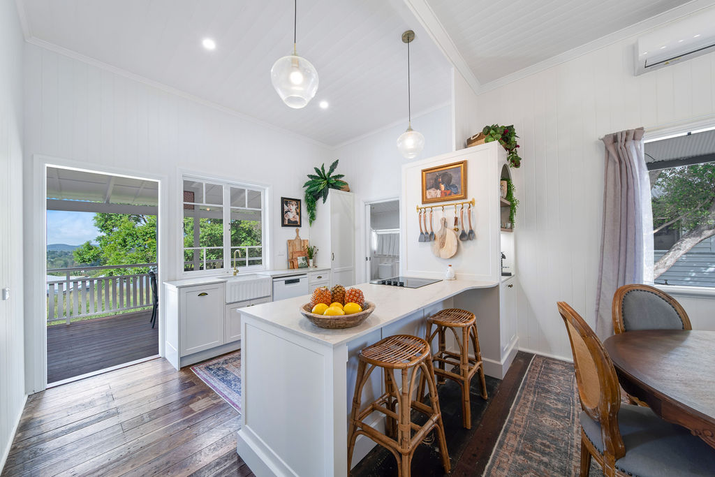 Renovated kitchen island with white cabinetry, timber floors and a compact breakfast stool.