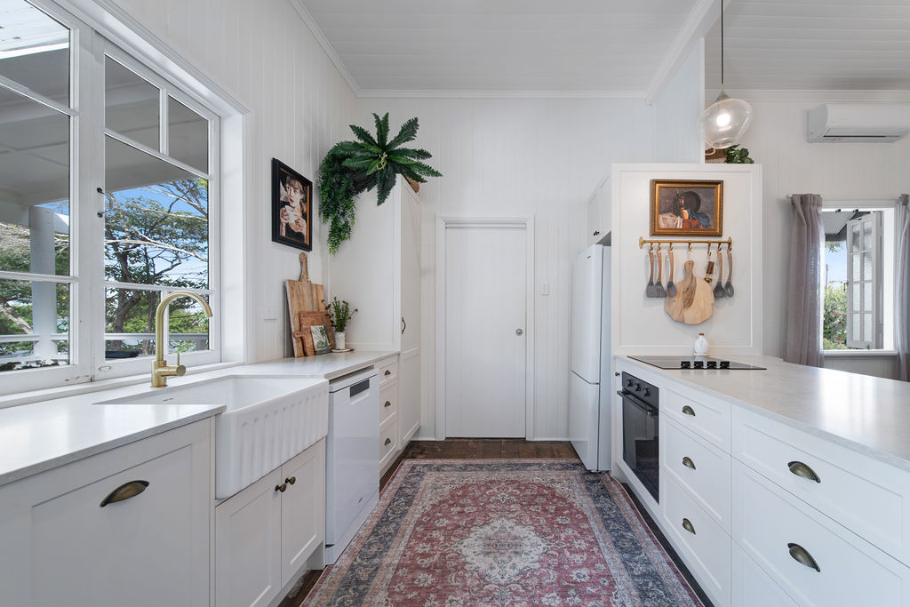 Renovated kitchen run with white cabinetry, black hardware and a vintage rug.
