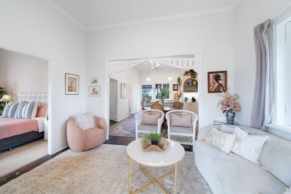 Wide view of the living room with pale seating, restored timber floors and original decorative trim.