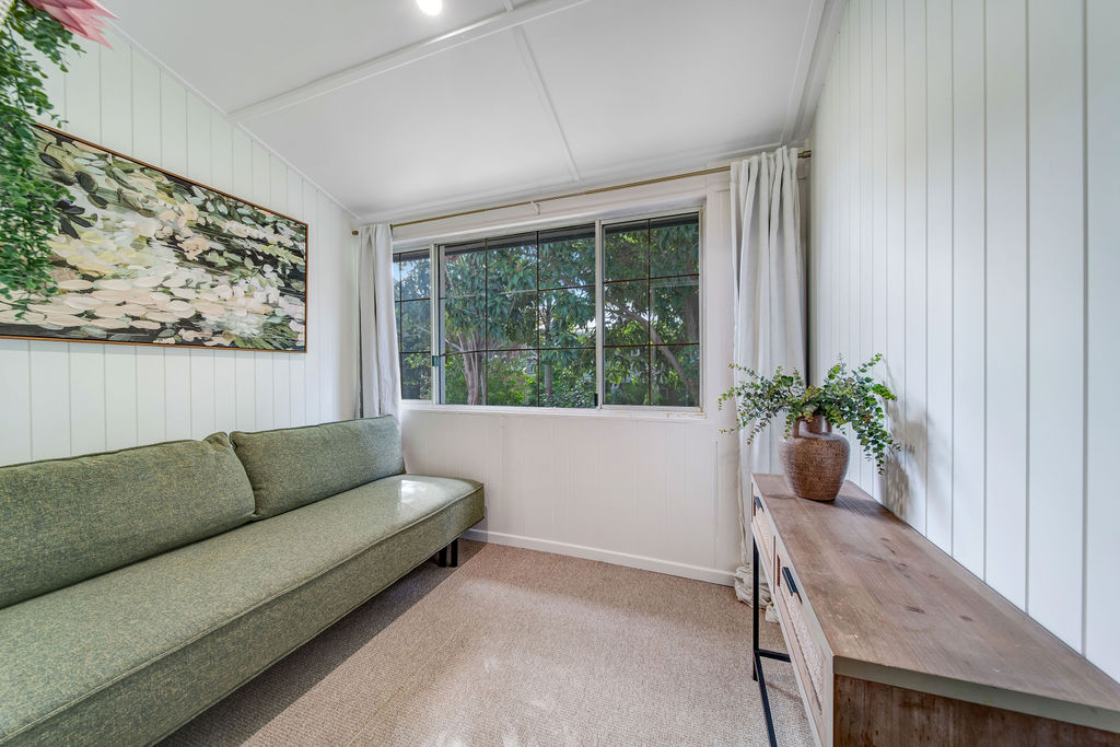 Sitting room with green sofa, white v-groove walls and a long timber console.