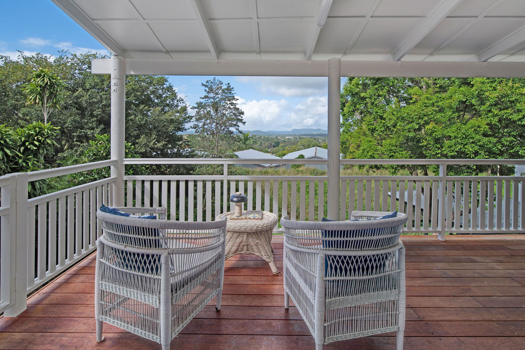 Verandah lounge setting with wicker chairs and views across the garden.