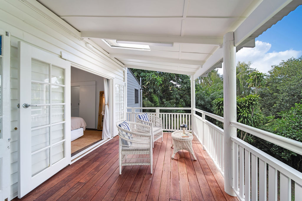 The verandah after renovation, with white balustrades, restored timber decking and a relaxed outdoor setting.