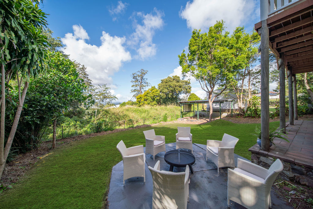 Garden and lawn with outdoor chairs under trees near the renovated home.