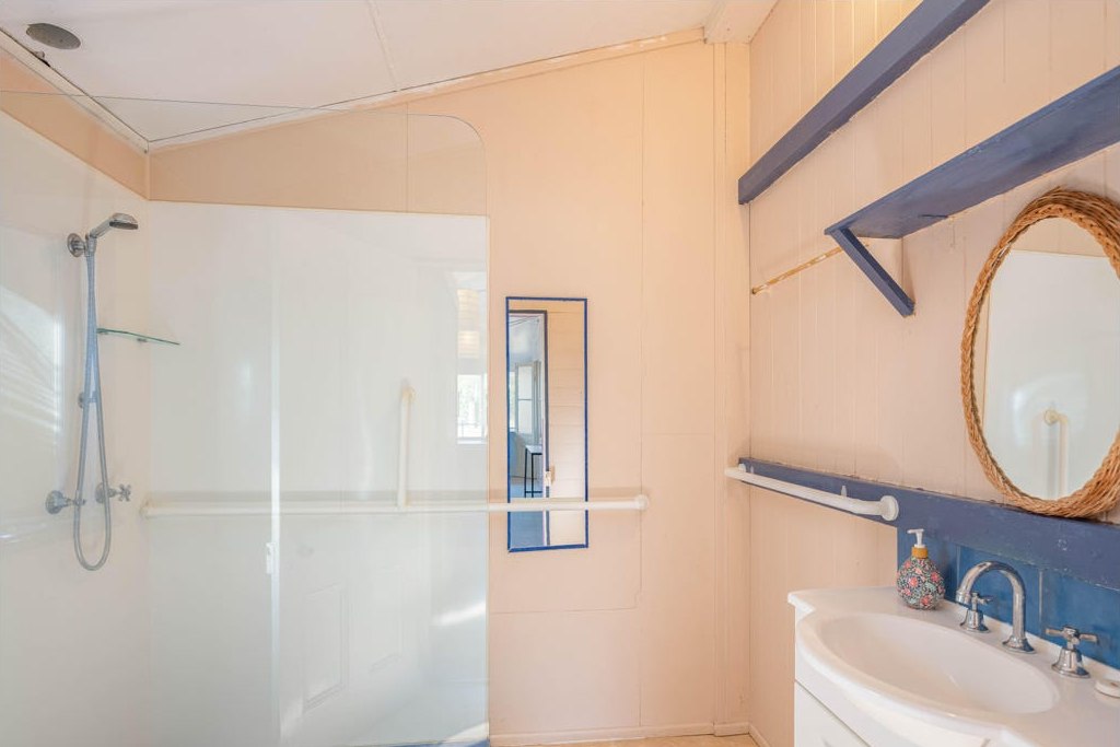 The bathroom before renovation, with peach walls, exposed shower curtain rail and a dated vanity area.