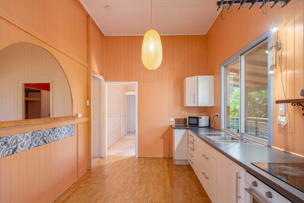 The kitchen before renovation, with peach wall panelling, basic cabinetry and a dated pass-through.