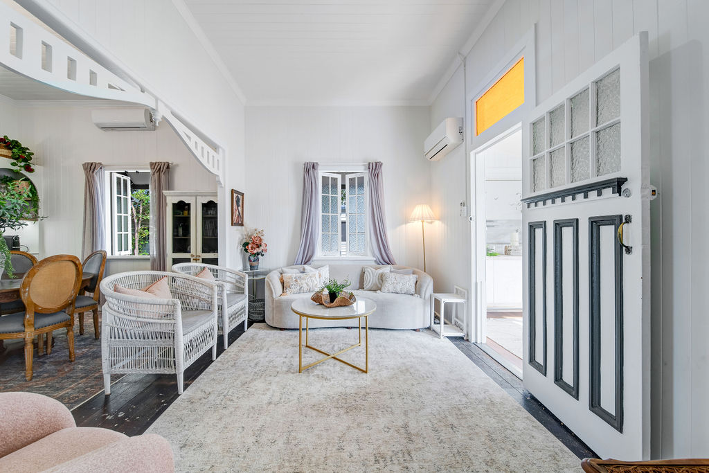 Light-filled living and dining room at Lady Mary Terrace with restored timber floors, white walls and layered furnishings.