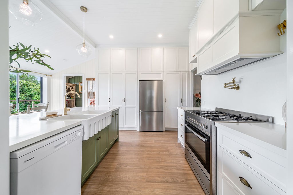 Renovated kitchen run with white cabinetry, timber floorboards and brass hardware.