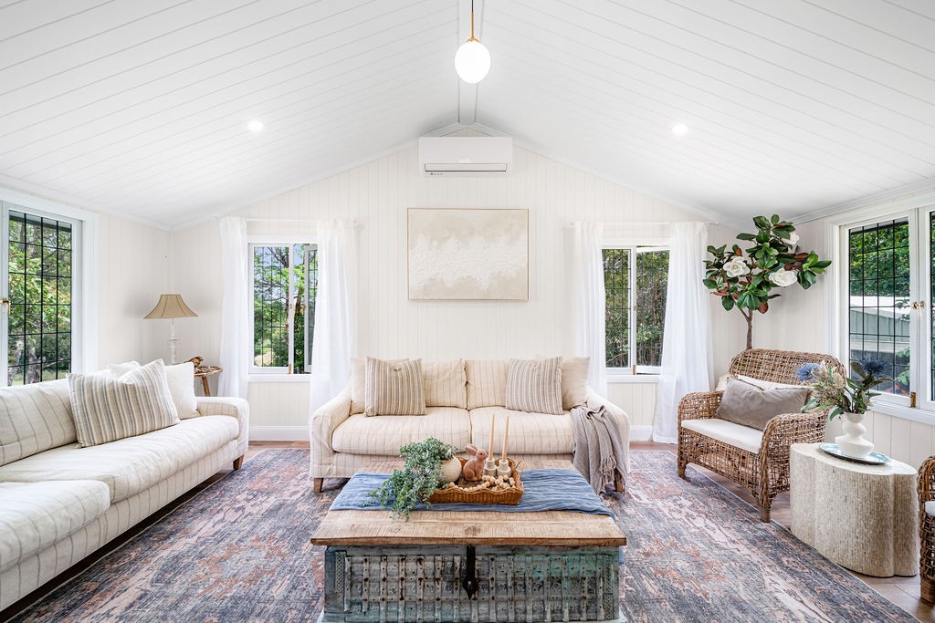The former verandah after renovation, transformed into a light-filled living room with pale seating.