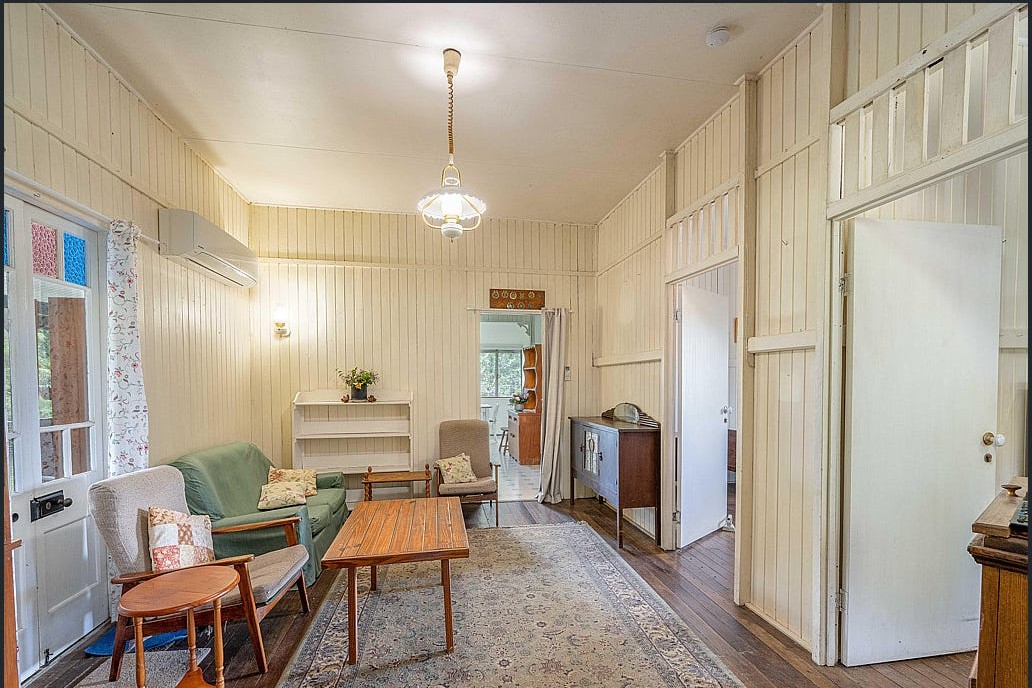 The dining room before renovation, with dated carpet, cream panelling and a closed-in layout.