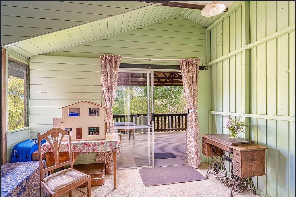 The original living room before renovation, enclosed by green wall panelling and dated carpet.