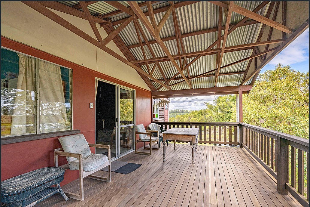 The verandah before renovation, with red exterior walls and old outdoor furniture.